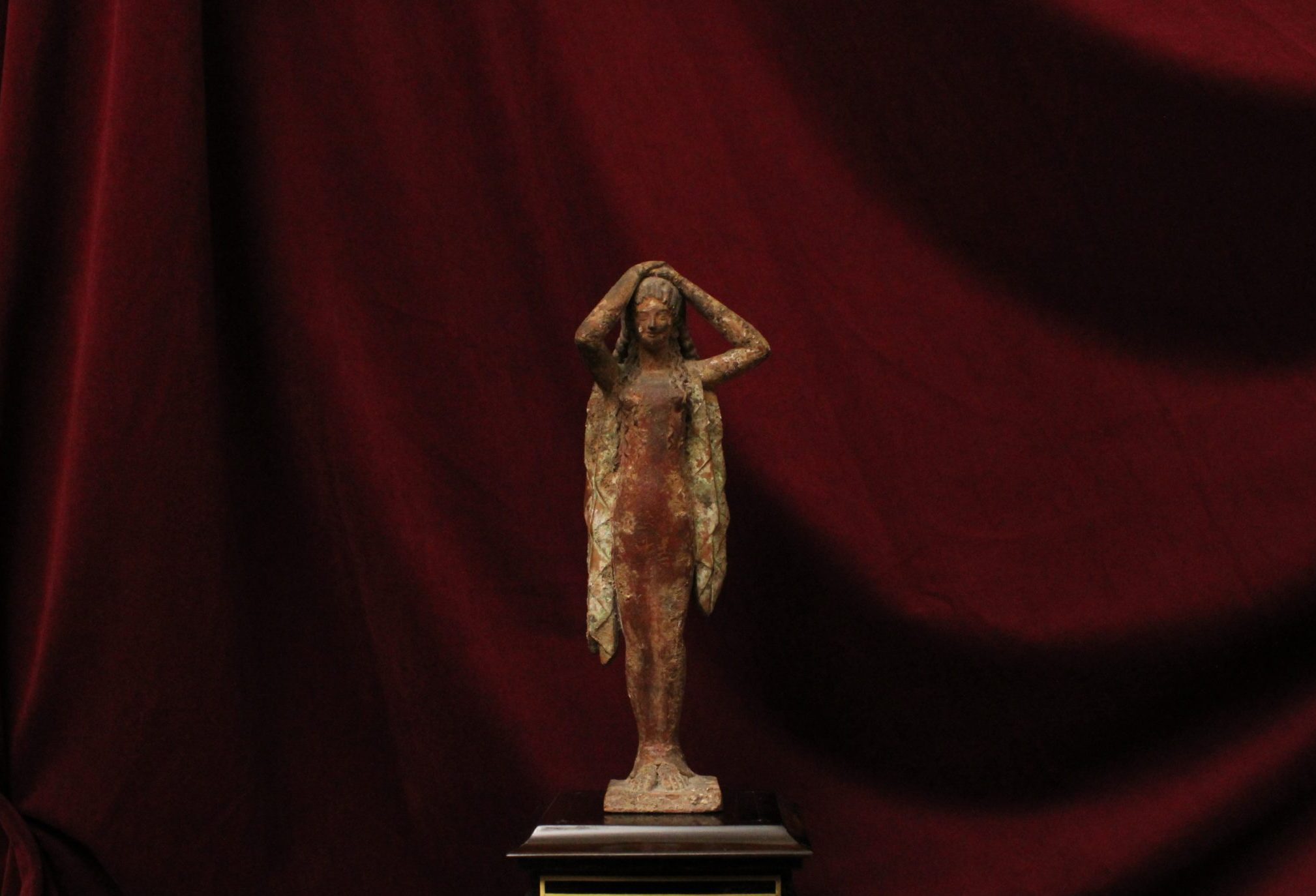 Statuette féminine, le corps gainé et les bras levés au-dessus de la tête, en terre cuite dans le goût des figures antiques de Korè.